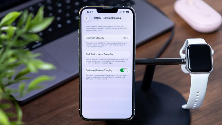 En iPhone på ett stativ bredvid en Apple Watch som visar menyn för batterihälsa